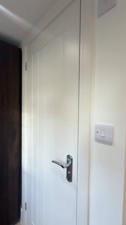 White panelled interior door with painted frame and surrounding pale wall